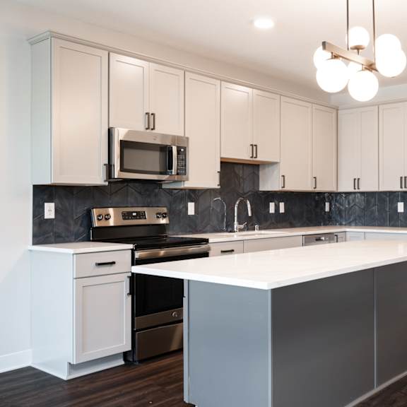 Thumbnail 3 of 15 Beautiful white kitchen with matching stainless steel appliances and large kitchen island.
