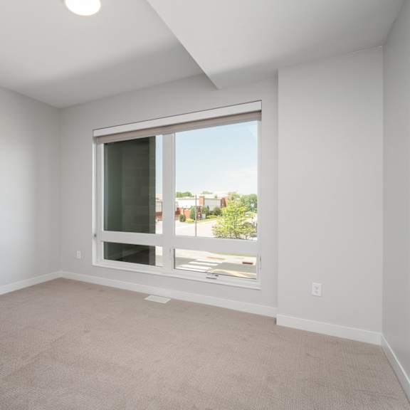 Thumbnail 6 of 15 Second bedroom with large floor to ceiling window, beige carpet, and white walls.
