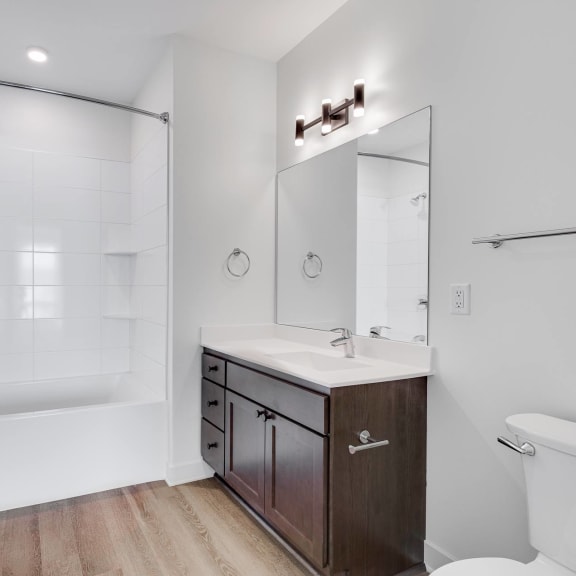 Thumbnail 7 of 8 Bathroom with dark brown vanity and linen cabinet for storage and large mirror at The Rowan in Eagan Minnesota