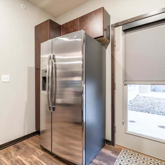 Thumbnail 6 of 21 A stainless steel refrigerator is in a kitchen with wood cabinets.