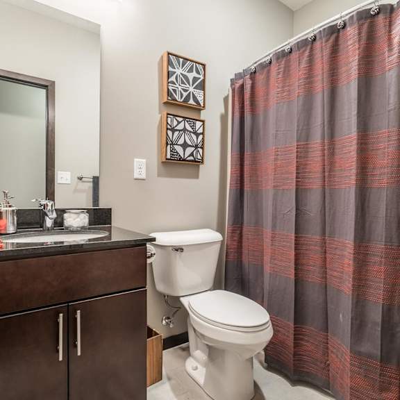 Thumbnail 11 of 21 A bathroom with a toilet, sink, and shower curtain.