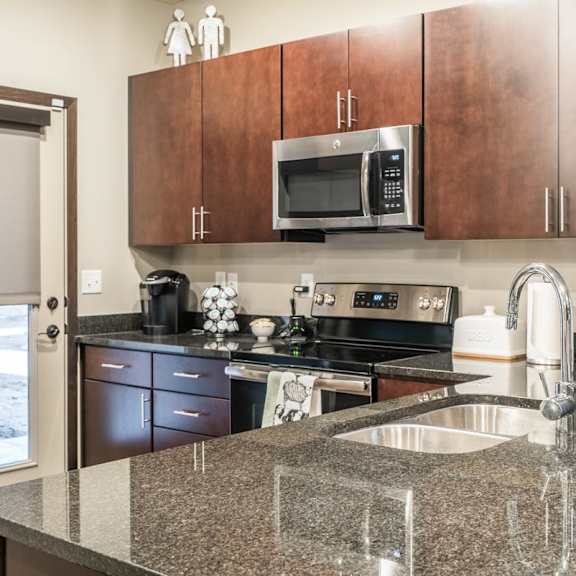 a kitchen with cherry cabinets, granite counter top and stainless steel appliances.