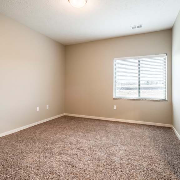 Thumbnail 4 of 14 A bedroom with a carpeted floor and a window with blinds.