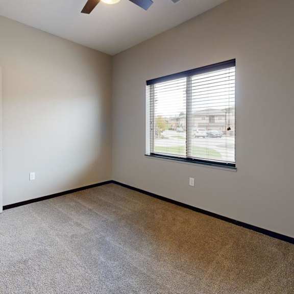 Thumbnail 7 of 9 A room with a white door, carpeted floor, and a window with blinds.
