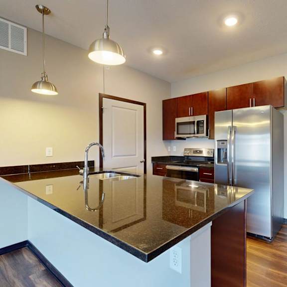 Thumbnail 4 of 9 A kitchen with a black granite countertop and stainless steel appliances.