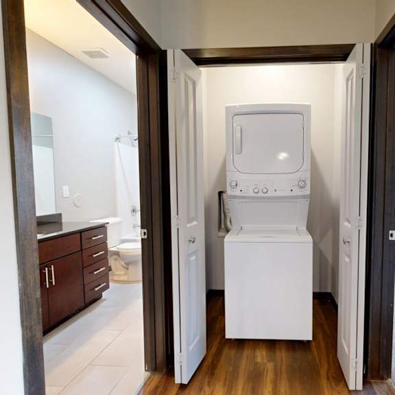 Thumbnail 6 of 9 A white washing machine/dryer is in a closet between two rooms.