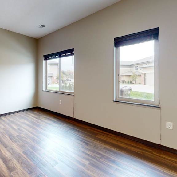 Thumbnail 5 of 9 A living  room with wooden flooring and two windows.
