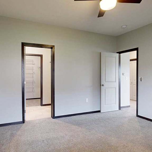 Thumbnail 21 of 25 A carpeted bedroom with an attached bathroom connected to a walk-in closet.
