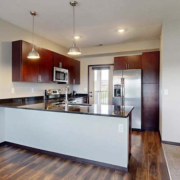 Thumbnail 11 of 25 A kitchen with dark wooden cabinets, granite countertops, stainless steel appliances, and a peninsula countertop.