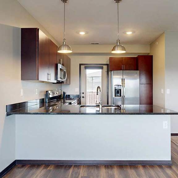Thumbnail 12 of 25 A kitchen with dark wooden cabinets, granite countertops, stainless steel appliances, and a peninsula countertop.