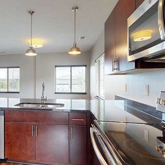Thumbnail 16 of 25 A kitchen peninsula with a double basin sink in front of a dining room and living room.