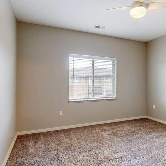 Thumbnail 24 of 26 A carpeted bedroom with a ceiling fan and a window.