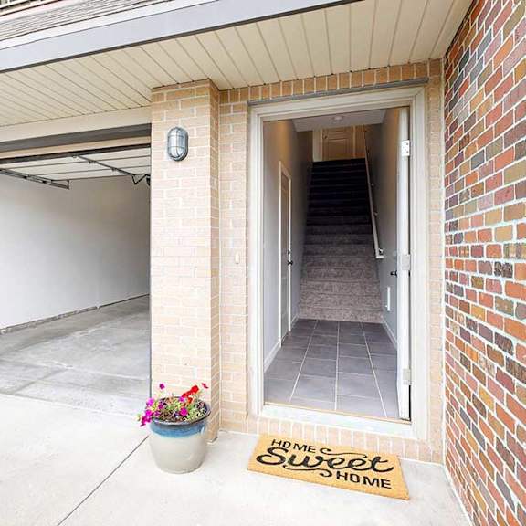 Thumbnail 4 of 26 An apartment front door open to a staircase, next to an open garage door.