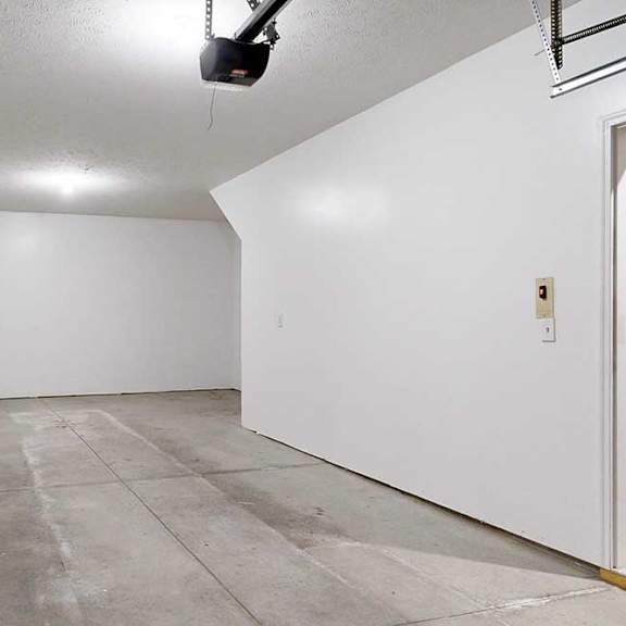 Thumbnail 5 of 26 A two-car tandem garage with an extra built-in storage space under the stairs.