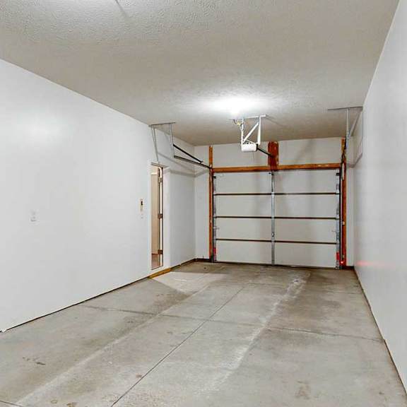Thumbnail 6 of 26 A two-car tandem garage with an extra built-in storage space under the stairs.