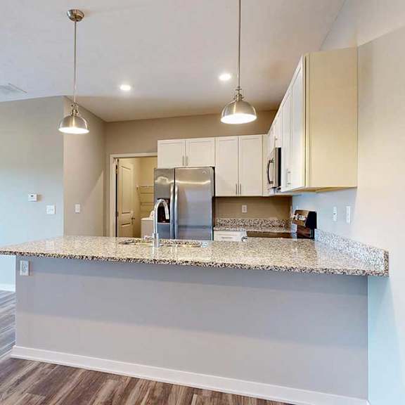 Thumbnail 11 of 26 A kitchen with white wooden cabinets, granite countertops, stainless steel appliances, and a peninsula countertop.