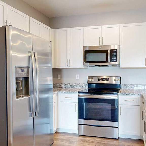 Thumbnail 13 of 26 A kitchen with white wooden cabinets, granite countertops, and stainless steel appliances.