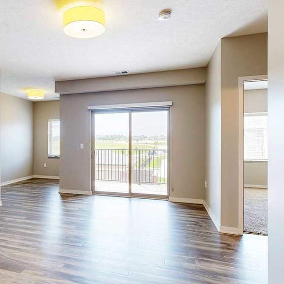 Thumbnail 18 of 26 A living room with hardwood-style flooring, a sliding glass door to a balcony, and a nook in the corner.