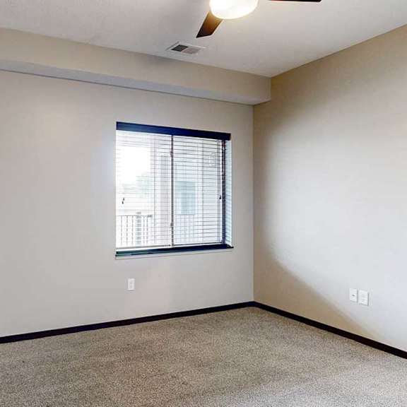 Thumbnail 21 of 24 A carpeted bedroom with a ceiling fan and a window.