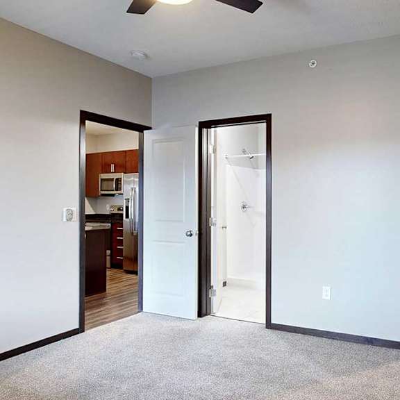 Thumbnail 19 of 24 A carpeted bedroom with an attached bathroom and walk-in closet.