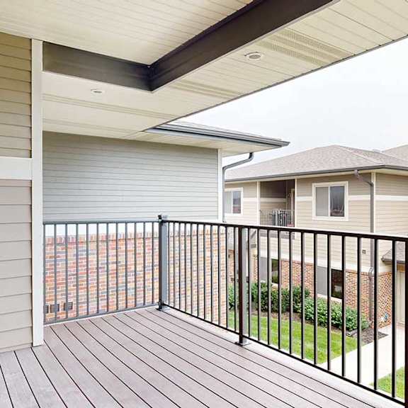 Thumbnail 17 of 24 A spacious balcony with a black metal railing and a view of the neighborhood.