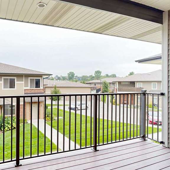 Thumbnail 18 of 24 A spacious balcony with a black metal railing and a view of the neighborhood.