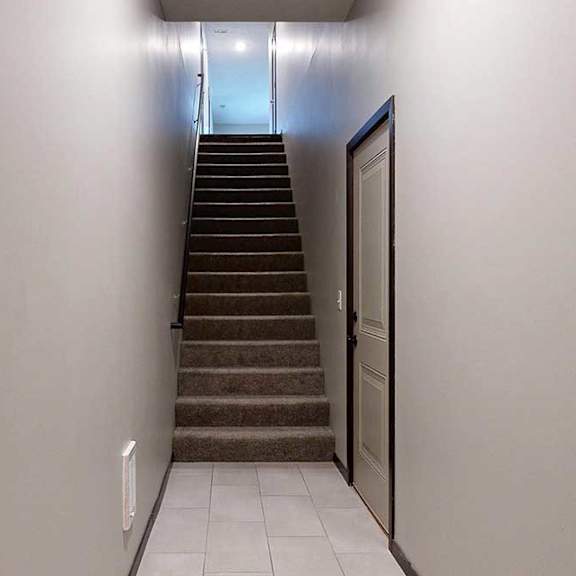 Thumbnail 3 of 24 An entryway with a closed door to the attached garage, and a stairway leading up to the living area.
