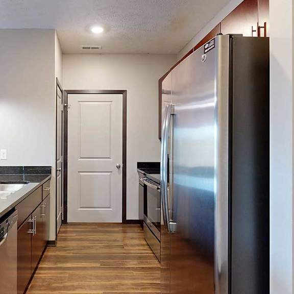 Thumbnail 8 of 24 A galley kitchen with dark granite countertops, dark wooden cabinets, and stainless steel appliances.