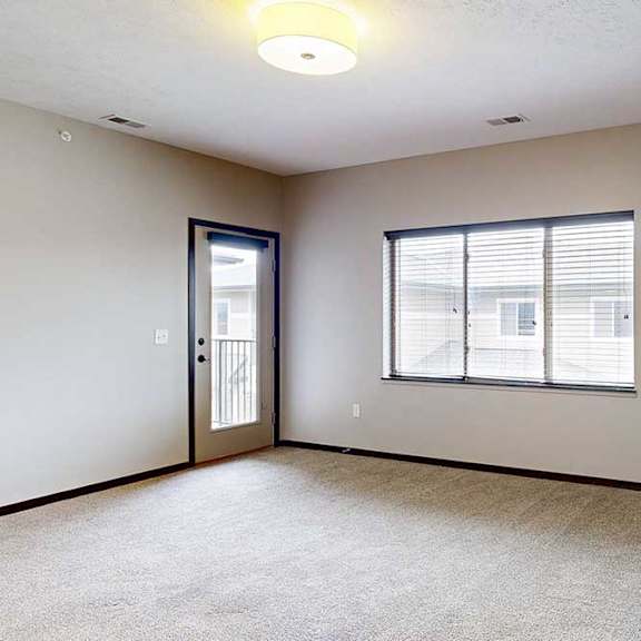 Thumbnail 15 of 24 A carpeted living room with a large window, an electric fireplace, and a windowed-door to the balcony.