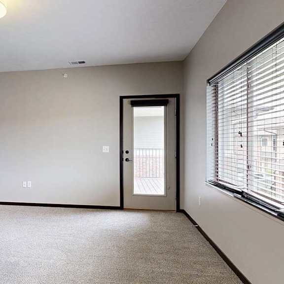 Thumbnail 16 of 24 A carpeted living room with a large window and a windowed-door to the balcony.