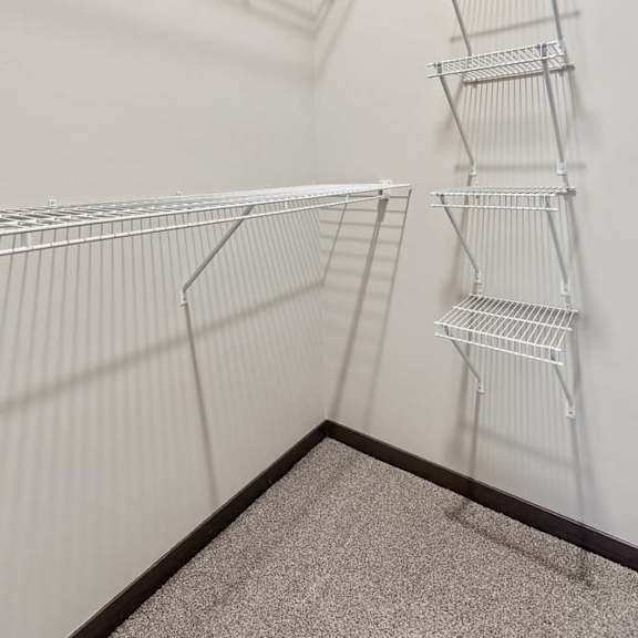 Thumbnail 14 of 14 Walk-in closet with white wire shelving, carpeted flooring, and ample storage space for apartment living.