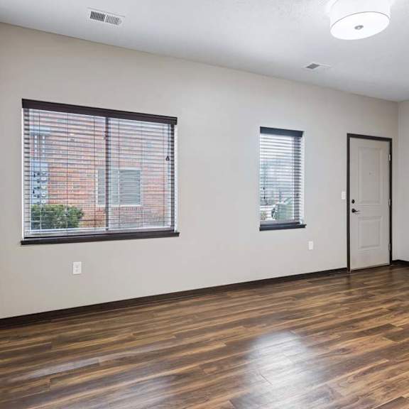 Thumbnail 5 of 14 Spacious living room with wood-style flooring, large windows, and an open layout connected to the kitchen area.