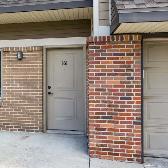 Thumbnail 4 of 18 Private apartment entry with brick exterior, covered front porch, and private front door with exterior lighting.