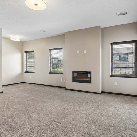 Thumbnail 8 of 18 Open living room with corner fireplace, multiple windows, and neutral finishes in an apartment home.