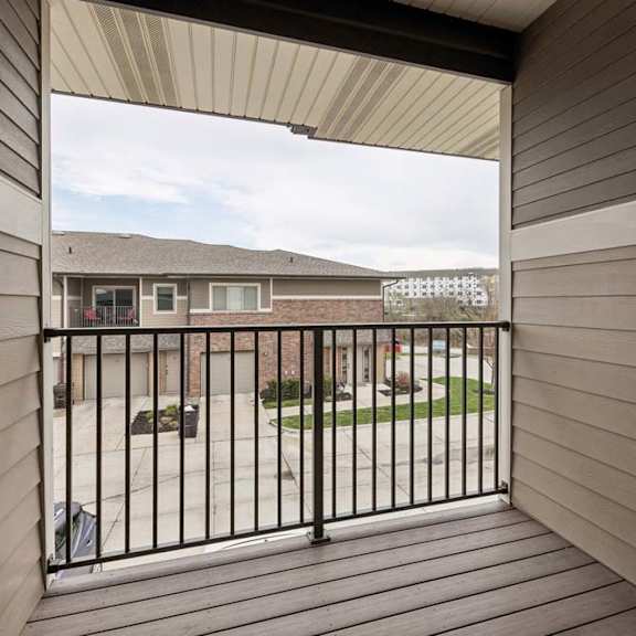 Thumbnail 9 of 14 A balcony with a black railing and a view of a building and a cloudy sky.