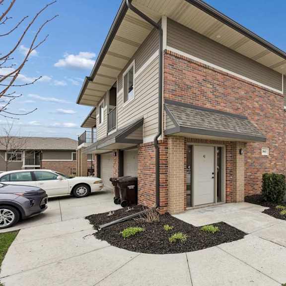 Thumbnail 3 of 14 A residential building with a brick facade and a white car parked in front.