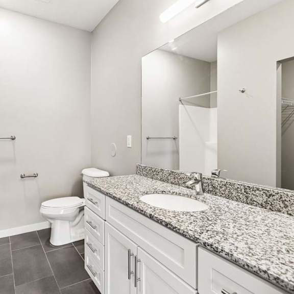 Thumbnail 19 of 21 A bathroom with a toilet, sink, and mirror.