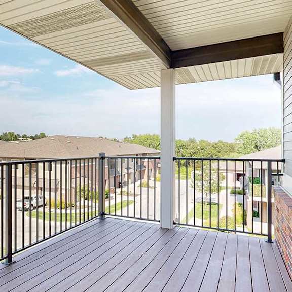 Thumbnail 10 of 26 A spacious balcony with a black metal railing and a view of the neighborhood.