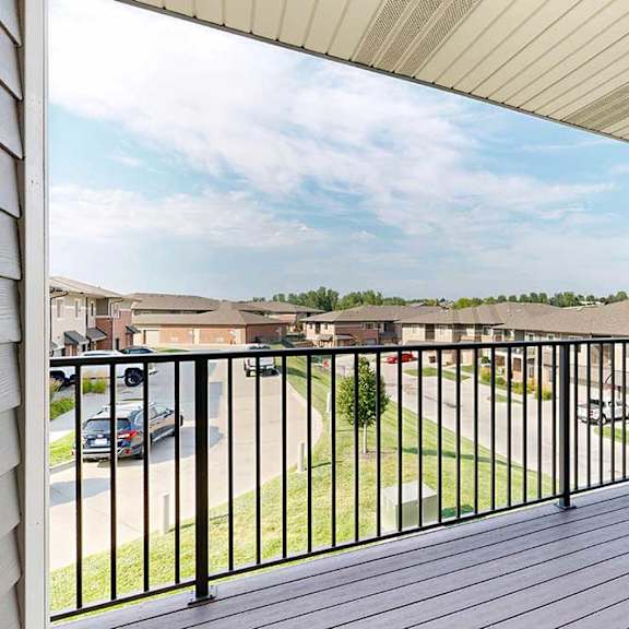 Thumbnail 11 of 26 A spacious balcony with a black metal railing and a view of the neighborhood.