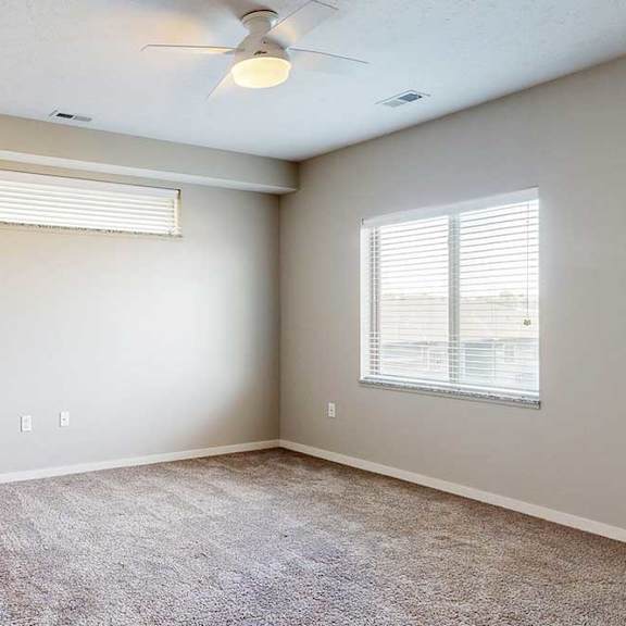 Thumbnail 14 of 26 A carpeted bedroom with a ceiling fan, a large window, and an overhead half-window.