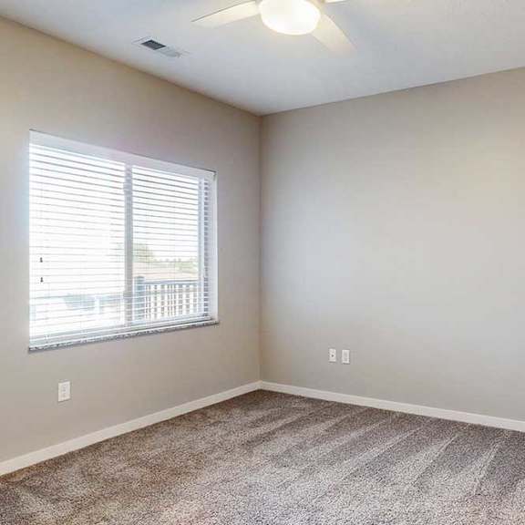 Thumbnail 18 of 26 A carpeted bedroom with a large window and a ceiling fan.