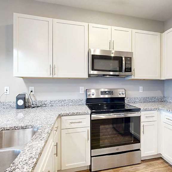 Thumbnail 4 of 26 A kitchen with white wooden cabinets, granite countertops, stainless steel appliances, and a peninsula countertop.