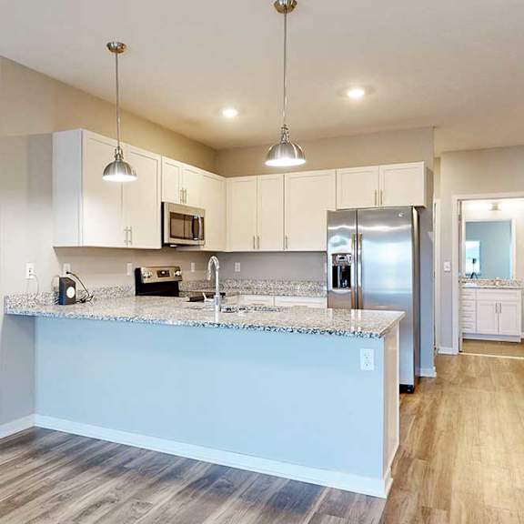Thumbnail 21 of 26 A kitchen with white wooden cabinets, granite countertops, stainless steel appliances, and a peninsula countertop.