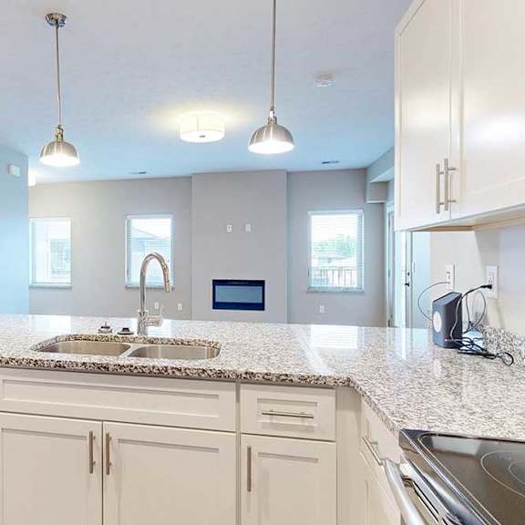 Thumbnail 16 of 26 A kitchen peninsula with a double basin sink in front of a living room.