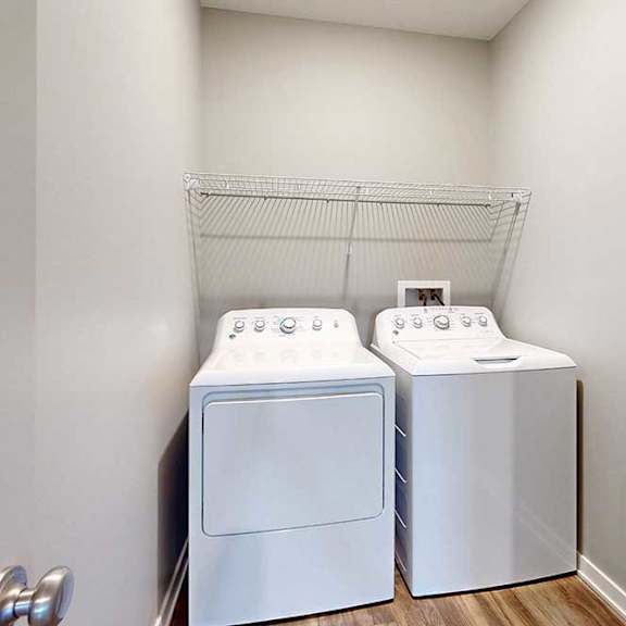Thumbnail 17 of 26 A side-by-side washer and dryer in a laundry room with overhead shelving.