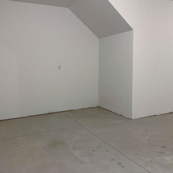 Thumbnail 17 of 21 A white room with a concrete floor and a white wall.