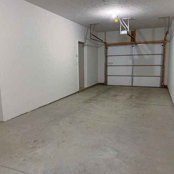 Thumbnail 16 of 21 A large empty garage with a white door and a white ceiling light.