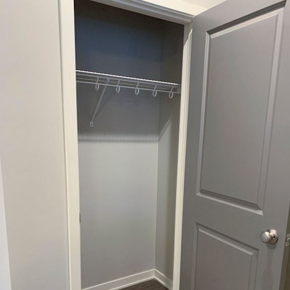 Thumbnail 6 of 21 A white closet with a grey door and a grey shelf.