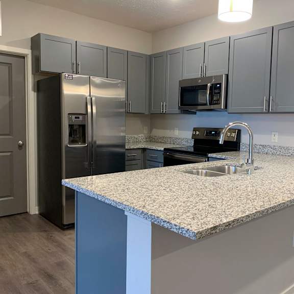 Thumbnail 5 of 21 A kitchen with a granite countertop and stainless steel appliances.