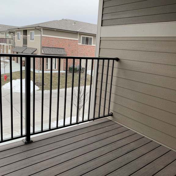 Thumbnail 14 of 21 A balcony with a black railing and wooden floor.